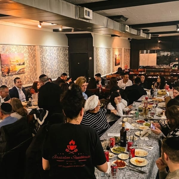 A bustling restaurant interior with many patrons seated at long tables, enjoying meals and conversation.
