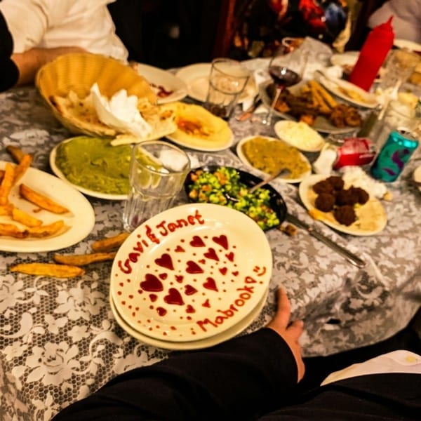 A table laden with various dishes, including fries, dips, and a celebratory plate for "Gavi & Janet."
